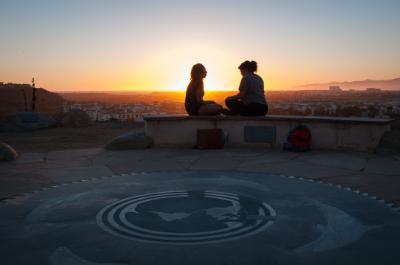 2 LMU members siting on a cement bench looking at the sunset